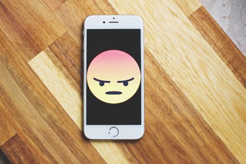 angry emoji on a smart phone laying on wood floor